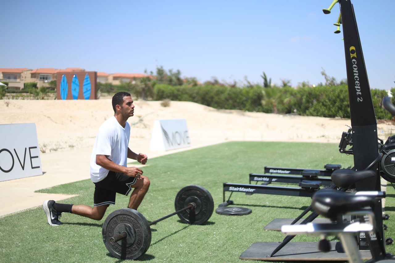 Man working out with barbell outdoors, focusing on dynamic fitness and strength.
